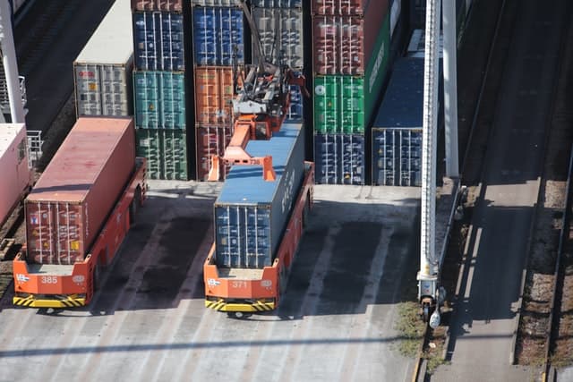 Overhead view of a crane loading a shipping container onto a truck in a container yard