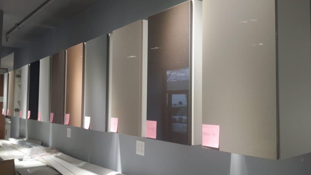Row of wall cabinets with glossy and wood-grain door samples, each with a pink sticky note