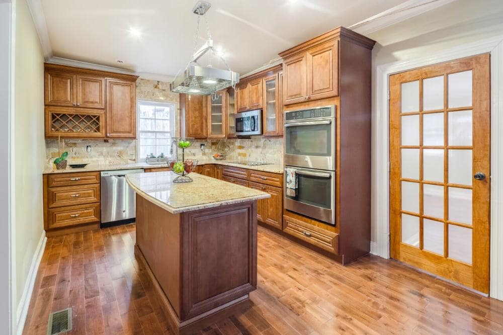 Kitchen with warm wood cabinets, island with granite top and double wall ovens