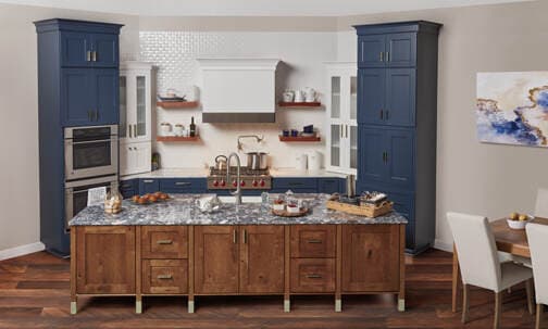 Kitchen with navy tall cabinets, wood island base and patterned stone countertop