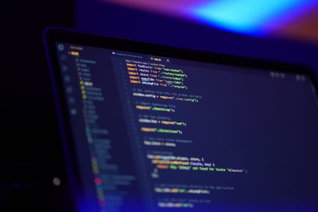 Blurred laptop screen showing lines of JavaScript code in a code editor