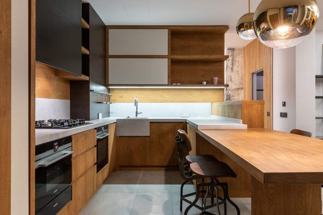 Modern kitchen with oak base cabinets, open shelving, a wooden breakfast bar and globe pendant lights