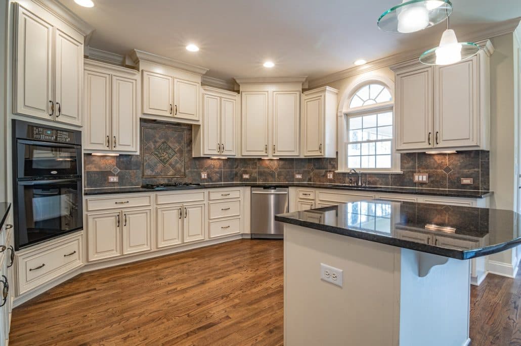 Kitchen with cream cabinets, dark granite counters, wall ovens and hardwood floor